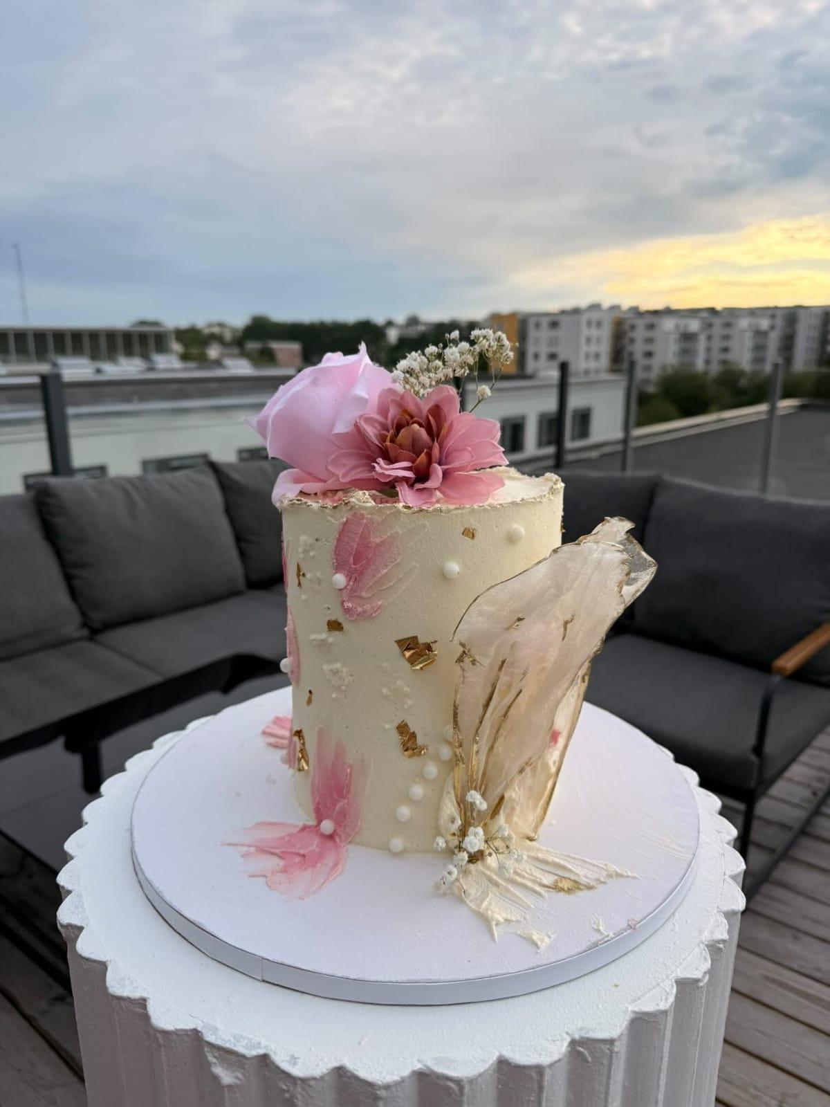 Elegant festtårta med rosa sockerblomma, fjädrar och guldflingor